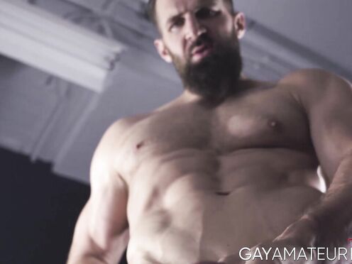 Bushy hunk Chuck Conrad works his fat cock with his two hands after flexing