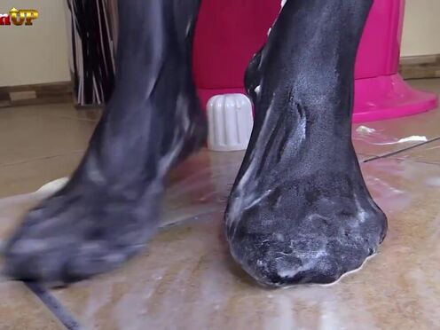 Brunette in pantyhose gives footjob to a cream tube